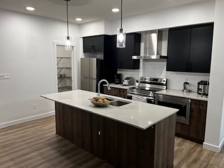 A modern kitchen with a central island, stainless steel appliances, and black cabinets.. Lakeview Oasis