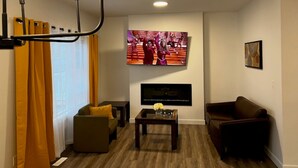 Ein Wohnzimmer mit Flachbildfernseher, Sofa, Couchtisch und braunem Ledersofa.