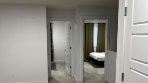 Ein Flur mit Teppichböden, weißen Wänden und einem Bett, dessen Hintergrund von einem grünen Vorhang verdeckt wird.