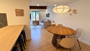 Een eetruimte met een ronde houten tafel, stoelen en een hanglamp.