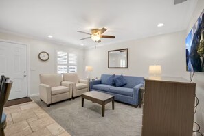 A living room with a ceiling fan, two sofas, a coffee table, and a wooden cabinet.