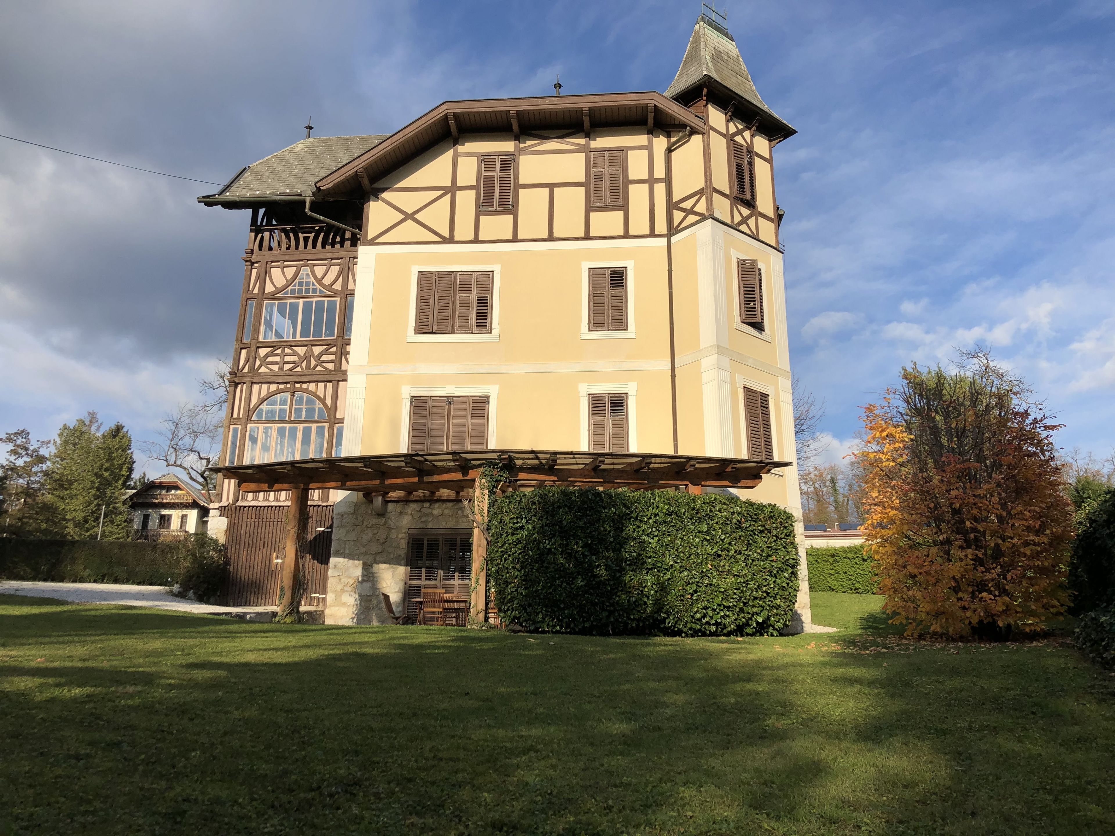 A multi-story building with a prominent tower, a covered porch, and a well-maintained lawn.