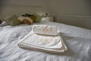 A neatly made bed with a folded white towel and a smaller towel with embroidered initials on a hotel room. - Villa Plemelj - Apartment Plemelj - sleeps 2 guests  in 1 bedroom (Bled)