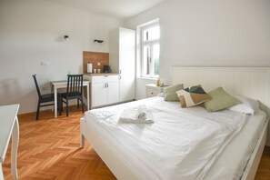 Un dormitorio con cama, escritorio, silla y ventana.