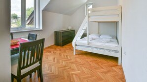 Et værelse med køjeseng, et spisebord med stole, et vindue og et gulv med et fisbenmønster.