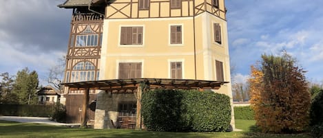 A multi-story building with a prominent tower, a covered porch, and a well-maintained lawn.