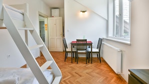 A room with a wooden floor, a dining table with chairs, a white staircase, and a window with blinds. - Villa Plemelj - All 4 Apartments - sleeps 8 guests  in 4 bedrooms (Bled)