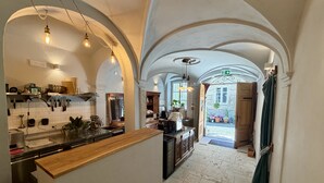 A kitchen with an island, white tiled walls, and wooden cabinets. There are hanging lights and a view of the outside through an open door. - Mini-Teater Suites - sleeps 18 guests  in 8 bedrooms (Ljubljana)