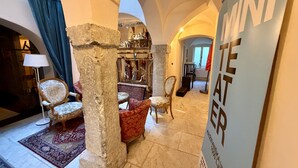 A hotel lobby with a stone column, a red patterned armchair, a white armchair, and a blue sign with the hotel's name. - Mini-Teater Suites - sleeps 18 guests  in 8 bedrooms (Ljubljana)
