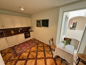 A compact kitchen with white cabinets, a dark countertop, and a patterned rug.