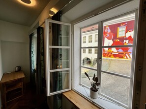 A room with a large window, a small table with a kettle, and a potted plant on the windowsill. - Mini-Teater Suites - Suite 3 - sleeps 2 guests  in 1 bedroom (Ljubljana)