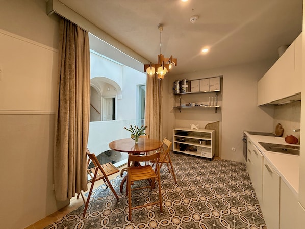 A compact kitchen with a dining area, patterned floor, and a view through a window.