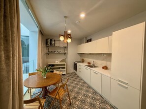 Una cocina moderna con armarios blancos, una mesa redonda de madera y baldosas de suelo con diseños.