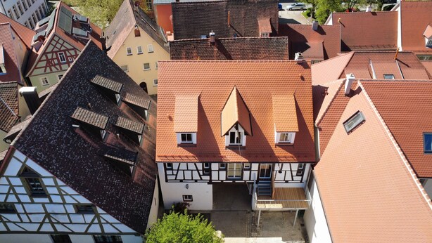 A traditional European building with a steeply pitched roof, dormer windows, and a visible chimney. - Historic horse stable in the center of Weißenburg (Weißenburg in Bayern)