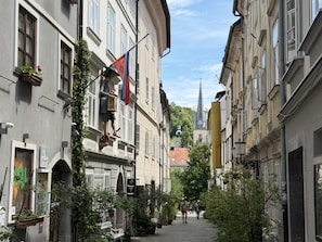 Eine schmale Straße gesäumt von historischen Gebäuden, eine Flagge und ein weiter in der Ferne sichtbarer Glockenturm.