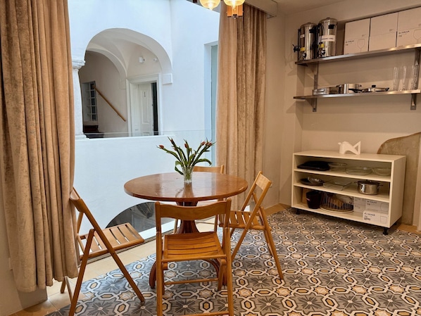 A dining area with a round table, chairs, a vase with flowers, and a patterned floor.