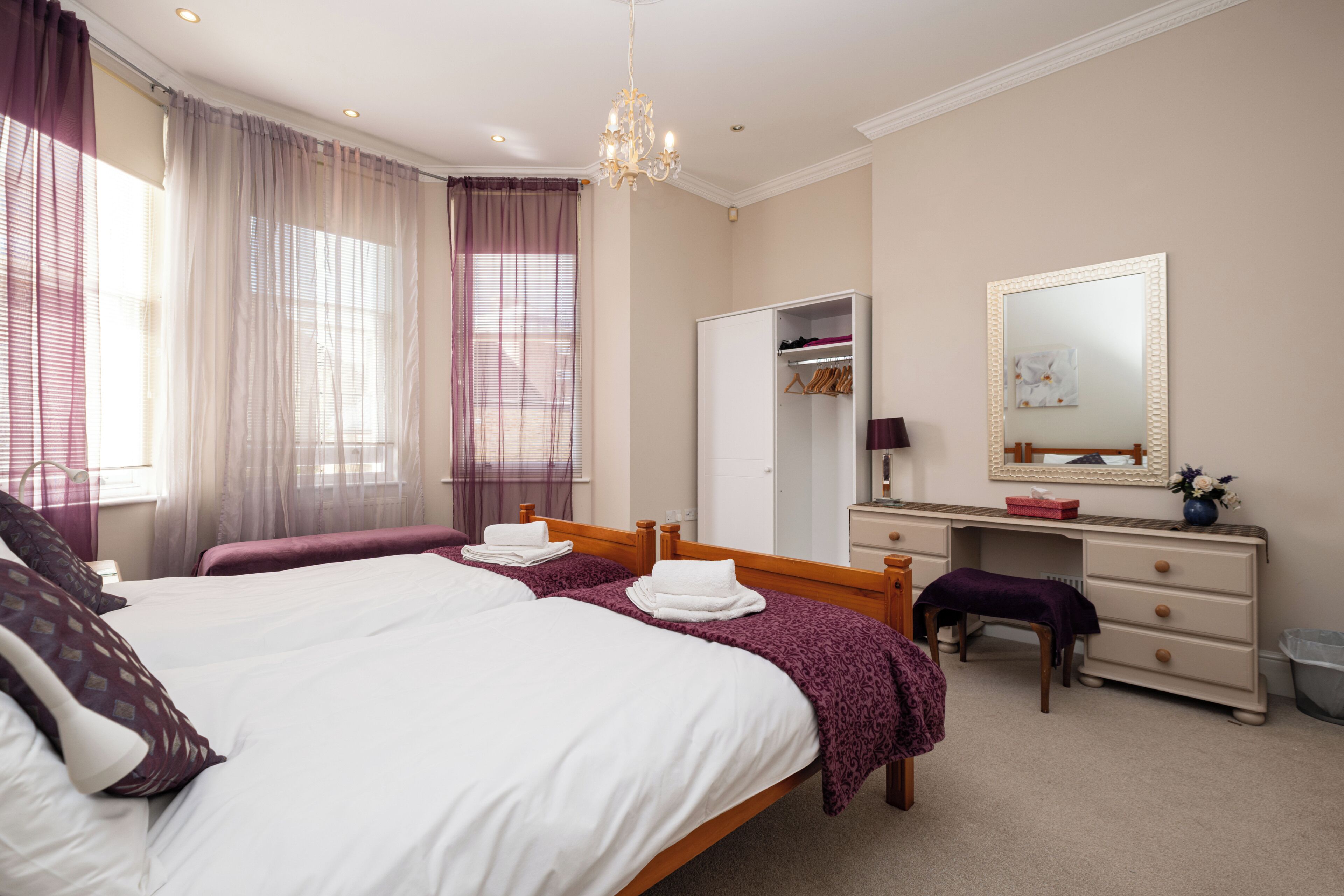 A hotel room with a large bed, a vanity with a mirror, and a wardrobe.