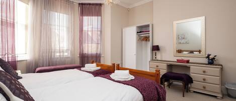 A hotel room with a large bed, a vanity with a mirror, and a wardrobe.