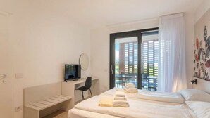 Ein Hotelzimmer mit einem Bett, einem Schreibtisch, einem Fernseher und Blick auf ein Gebäude.