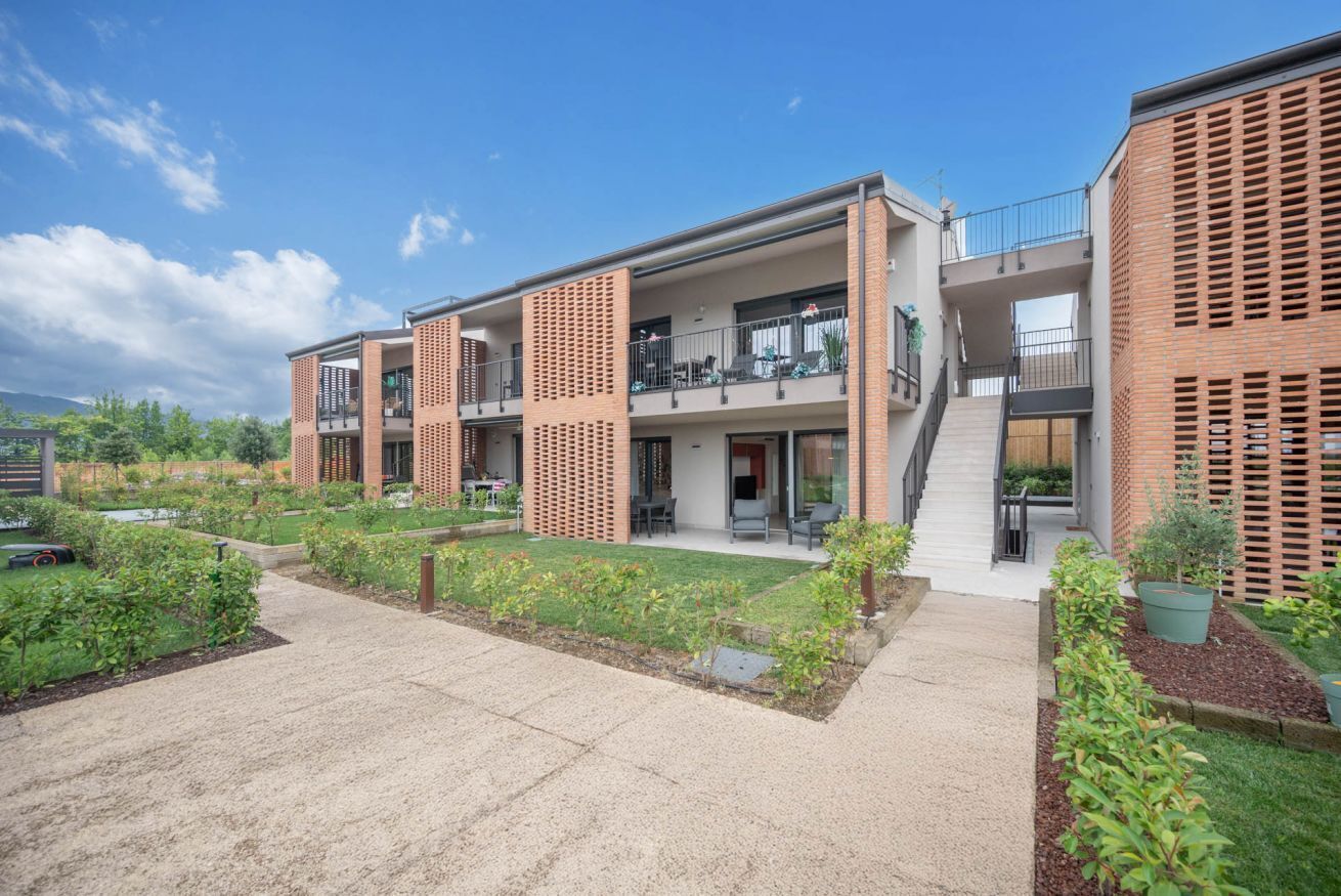 A modern multi-story building with balconies, a central courtyard, and a brick facade.