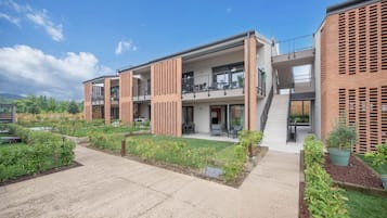 A modern multi-story building with balconies, a central courtyard, and a brick facade.