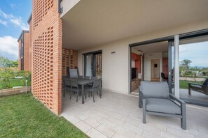 Un patio con una mesa, sillas, un sofá gris y una pared de ladrillo.