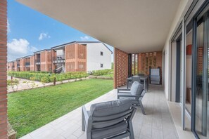 Un espacio al aire libre techado con patio, asientos y vista a un edificio de paredes de ladrillo y blanco.