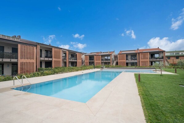 Un moderno edificio residencial con piscina, balcones y un cielo azul despejado.