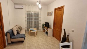 A compact living space with a sofa, a small table, a TV, and a decorative vase. - Torrevieja apartment next to the beach (Torrevieja)