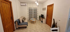 Ein kompakter Wohnraum mit einer Couch, einem kleinen Tisch, einem Fernseher und einer dekorativen Vase.
