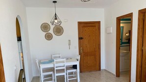 A dining area with a white table and chairs, a wooden door, and a wall with decorative plates. - Torrevieja apartment next to the beach (Torrevieja)