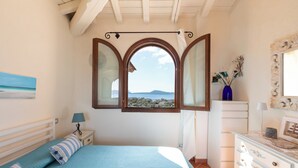 Un dormitorio con cama, cómoda, mesita de noche, ventana con vistas y un cuadro en la pared.
