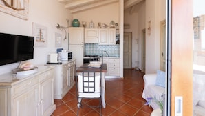 Una cocina con armarios blancos, una mesa de comedor y un televisor.