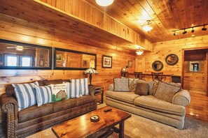 A cozy cabin interior with wooden walls, a sofa set, a dining table, and a ceiling fan. - Psalm 27 05 Relaxing Smoky Mountain Cabin | 3 Bedrooms, 4 Baths, Sleeps 10 (Sevierville)