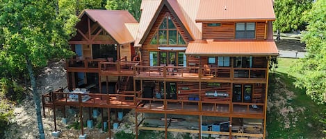 A multi-story log cabin with a deck and multiple rooms.