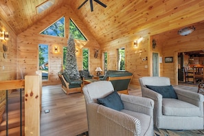 Ein Holzblockhaus-Interieur mit Holzwänden, einem Kamin, einem Weihnachtsbaum und einer gemütlichen Sitzecke.