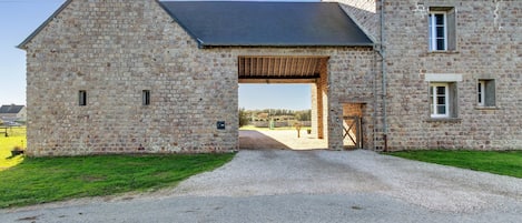Un edificio de piedra con un camino de grava que conduce a una puerta de madera.
