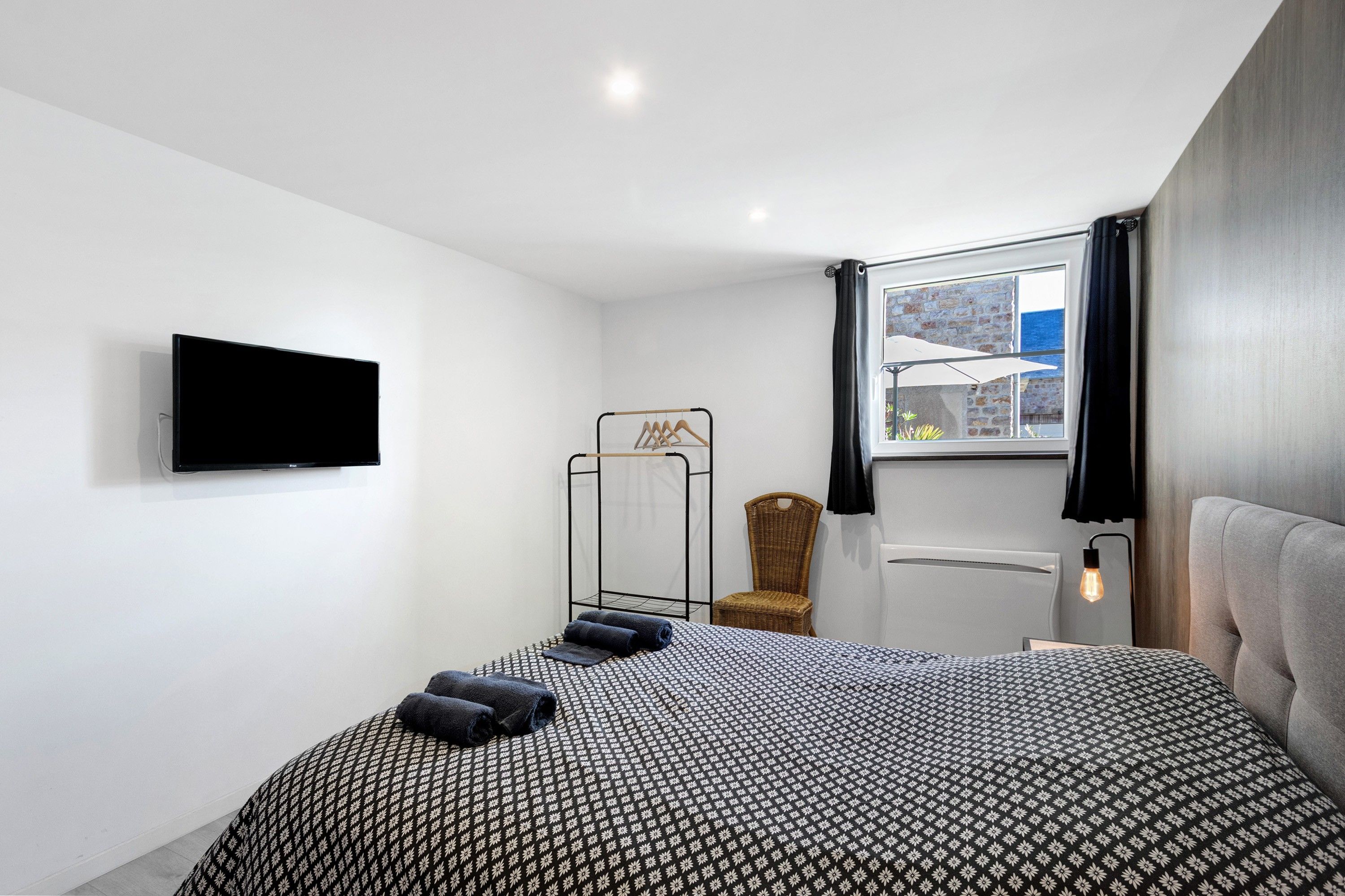 A modern bedroom with a bed, a television, a window with a view, and a chair.