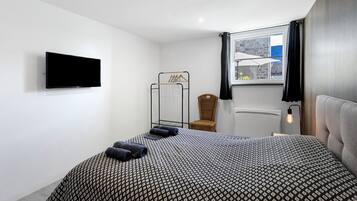 A modern bedroom with a bed, a television, a window with a view, and a chair.