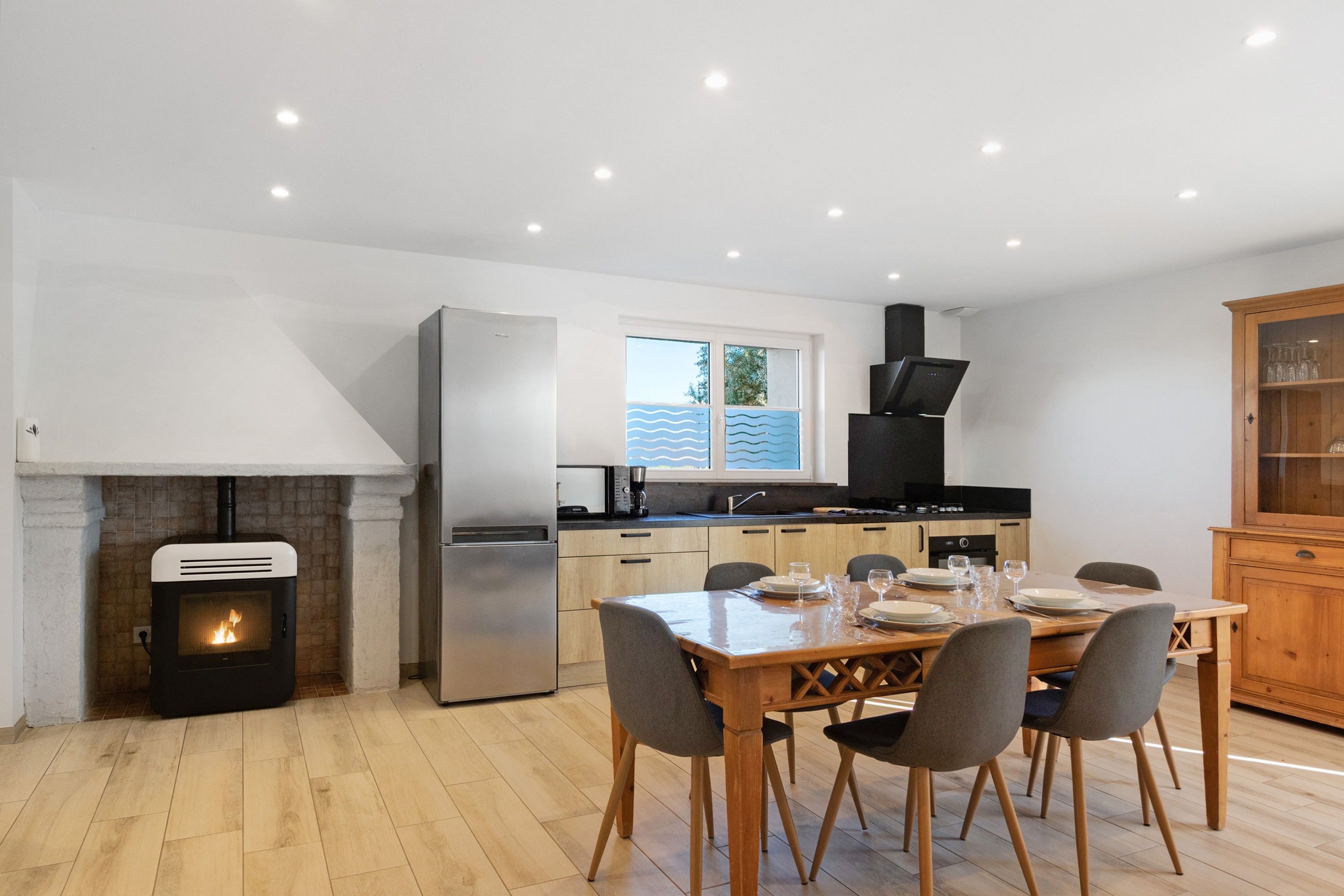 Une cuisine moderne équipée d’une cuisinière intégrée, d’un réfrigérateur et d’un coin repas avec une table et des chaises en bois.