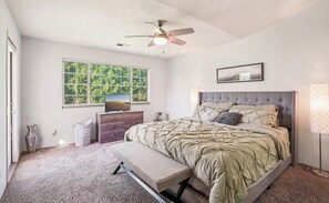 Ein Schlafzimmer mit Bett, Sitzbank, Kommode, Deckenventilator, Fenster und Lampe.