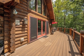 A wooden cabin with a deck, large windows, and a red door. - New! Dog Friendly Mountain Retreat w/Hot Tub (McHenry)