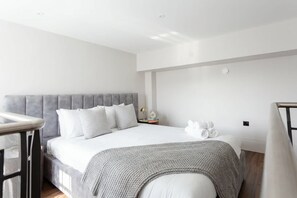 Ein modernes Hotelzimmer mit einem großen Bett, einem Nachttisch und einem kleinen Beistelltisch.