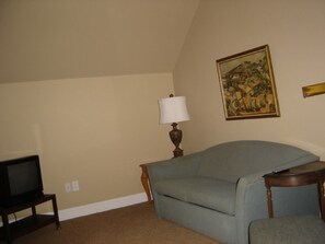 A living room with a sofa, a lamp, a painting, and a television. - Spacious 4-bedroom house in adorable Charlevoix with AC (Charlevoix)