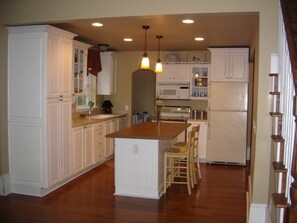 A kitchen with white cabinetry, a central island, and a microwave. - Spacious 4-bedroom house in adorable Charlevoix with AC (Charlevoix)