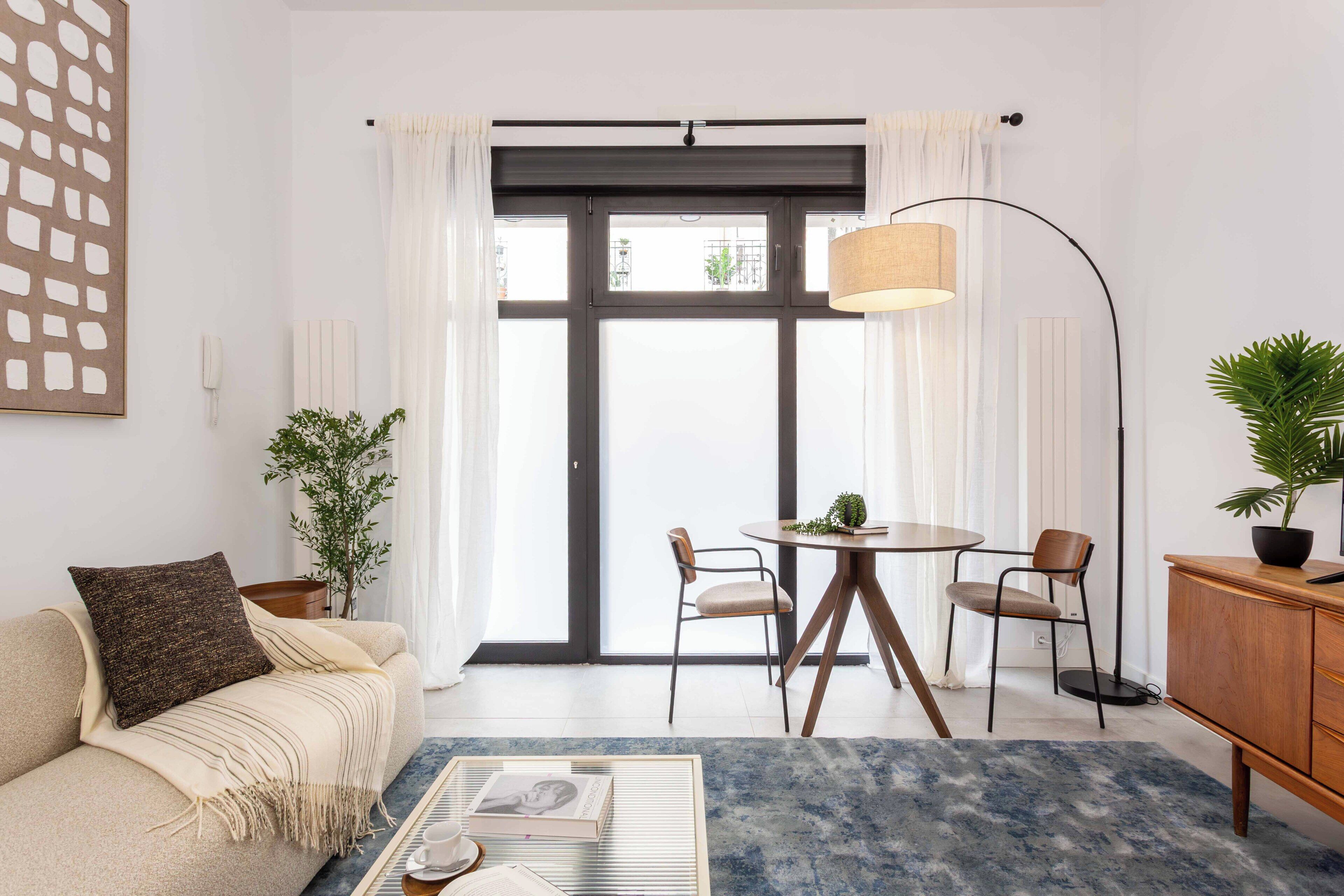 A modern living room with a sofa, coffee table, dining table, chairs, and a floor lamp.