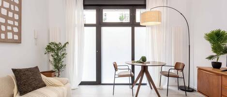 A modern living room with a sofa, coffee table, dining table, chairs, and a floor lamp.