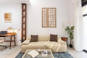 A modern living room with a sofa, coffee table, and a ladder against the wall. - A spacious furnished studio in the heart of Tetuán with its own private patio, for slow coffee in the morning or a workday in the sun. (MADRID)
