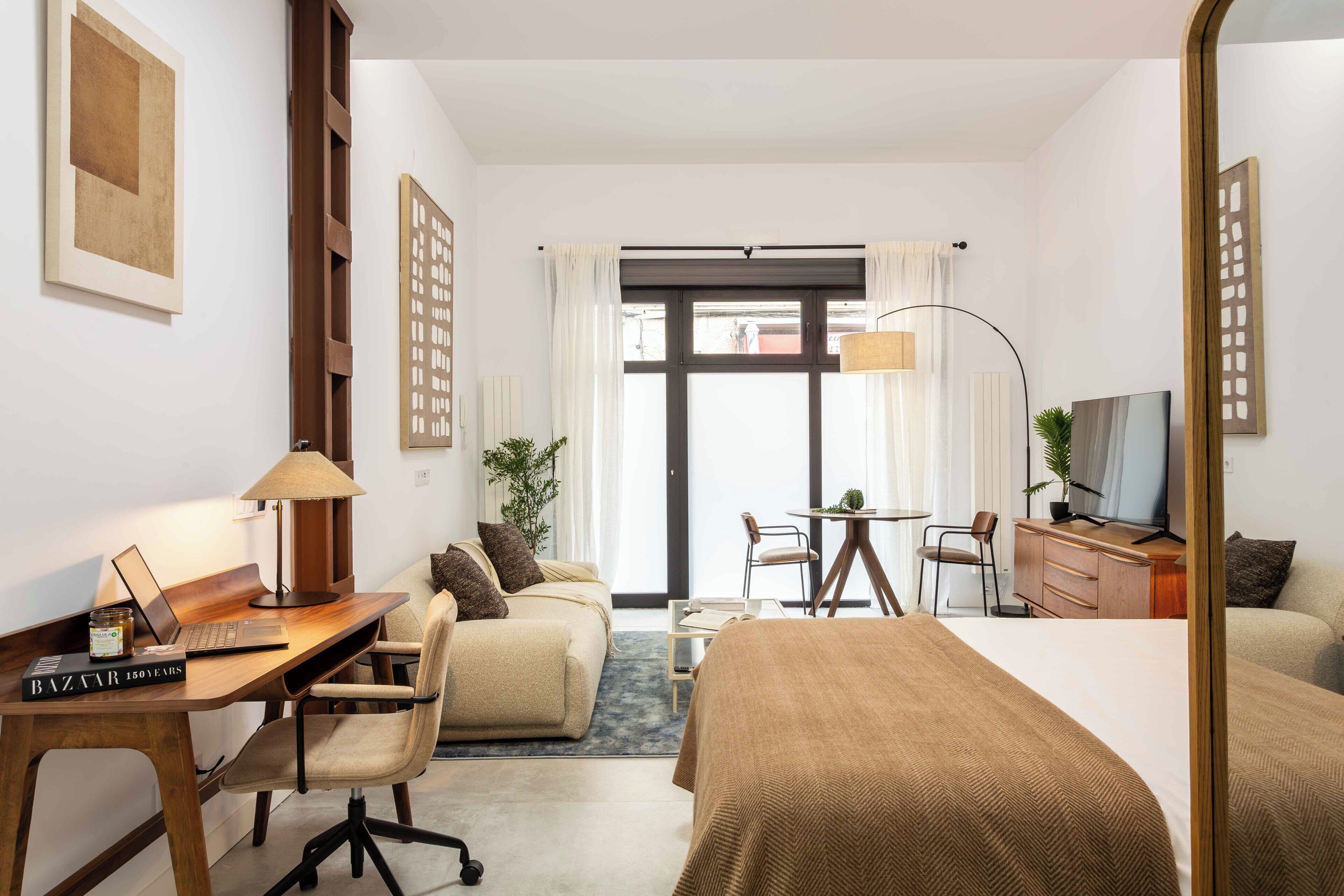 A hotel room with a bed, desk, chair, TV, and a view of the outdoors.