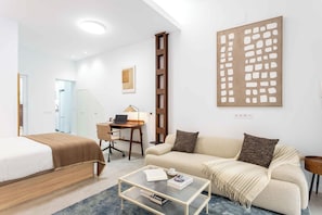 A modern hotel room with a bed, a sofa, a desk, and a coffee table. - A spacious furnished studio in the heart of Tetuán with its own private patio, for slow coffee in the morning or a workday in the sun. (MADRID)